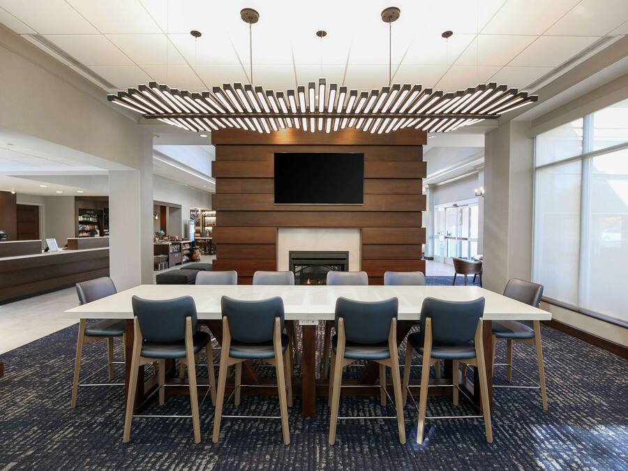 A conference room with a long table, six chairs, a fireplace, and a large TV screen.