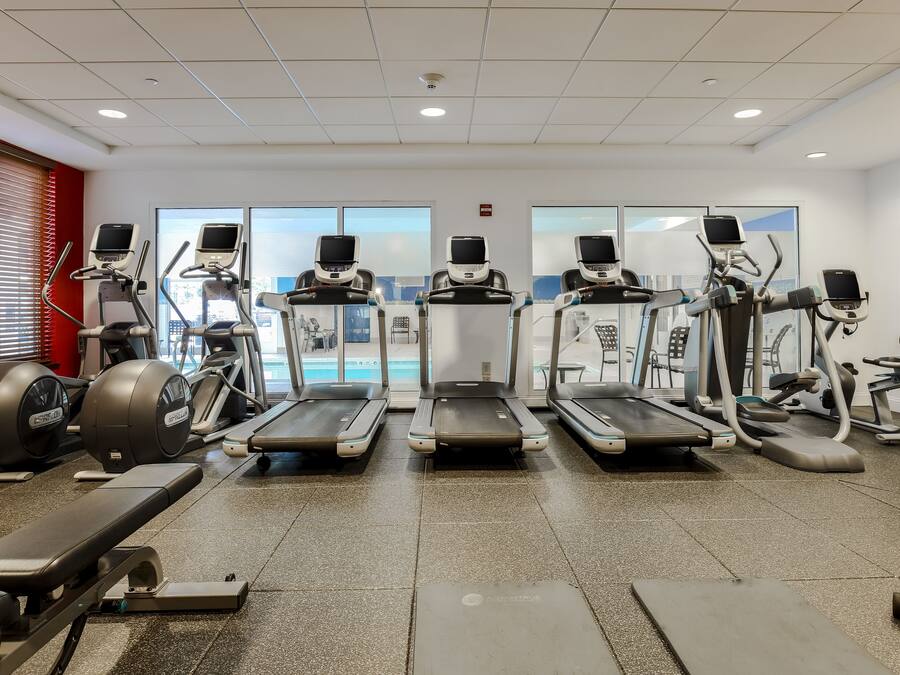 Une salle de sport équipée de tapis de course, de vélos elliptiques et de bancs de musculation.