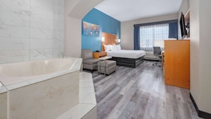 A hotel room with a large bathtub, a bed with a headboard, a desk with a chair, and a television. - La Quinta Inn & Suites by Wyndham Alvarado (Alvarado)