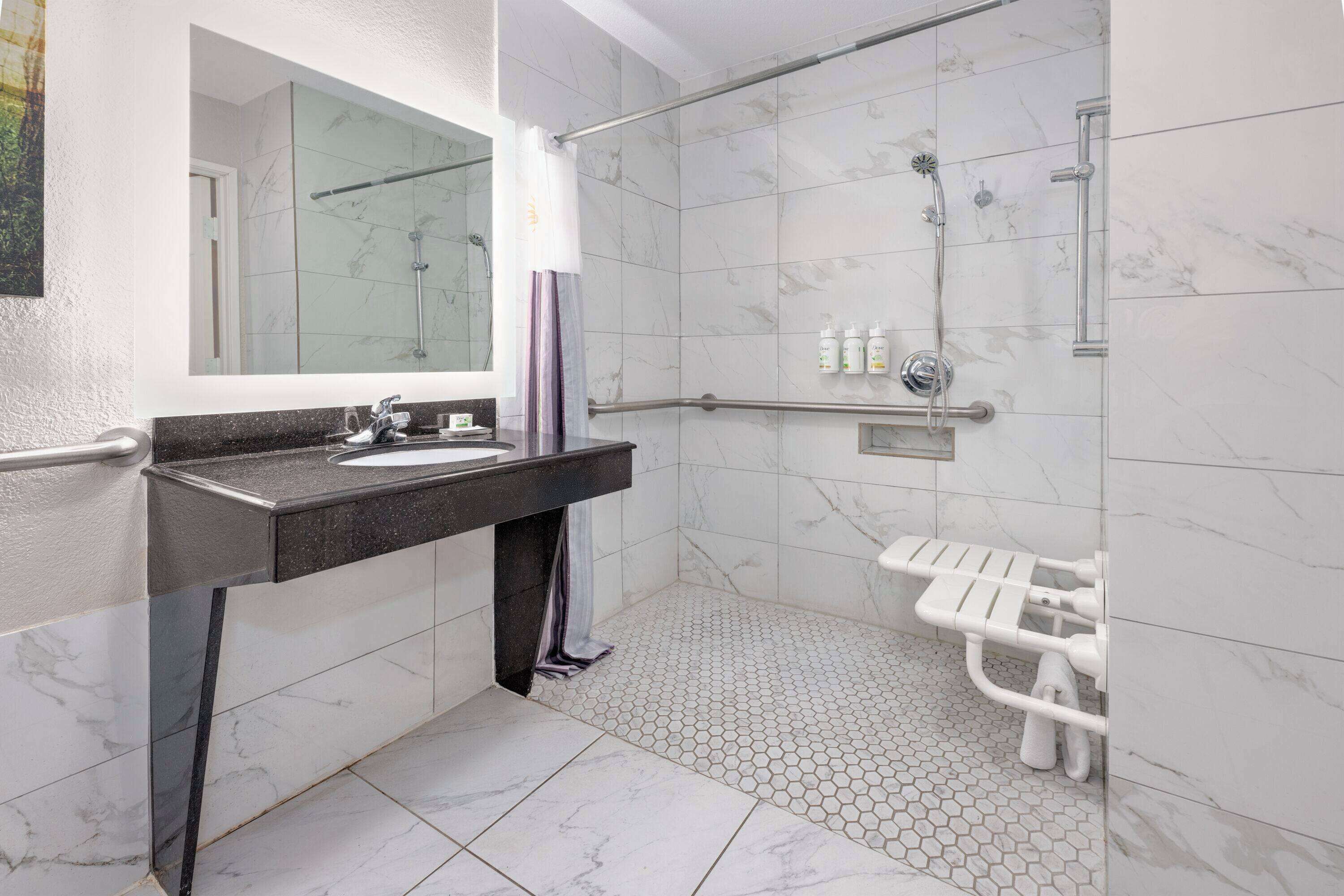 Une salle de bain moderne avec une douche carrelée de marbre, un meuble-lavabo et une cabine de douche en verre.