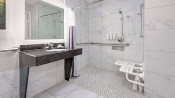 A modern bathroom with a marble-tiled shower, a vanity with a sink, and a glass-enclosed shower area.