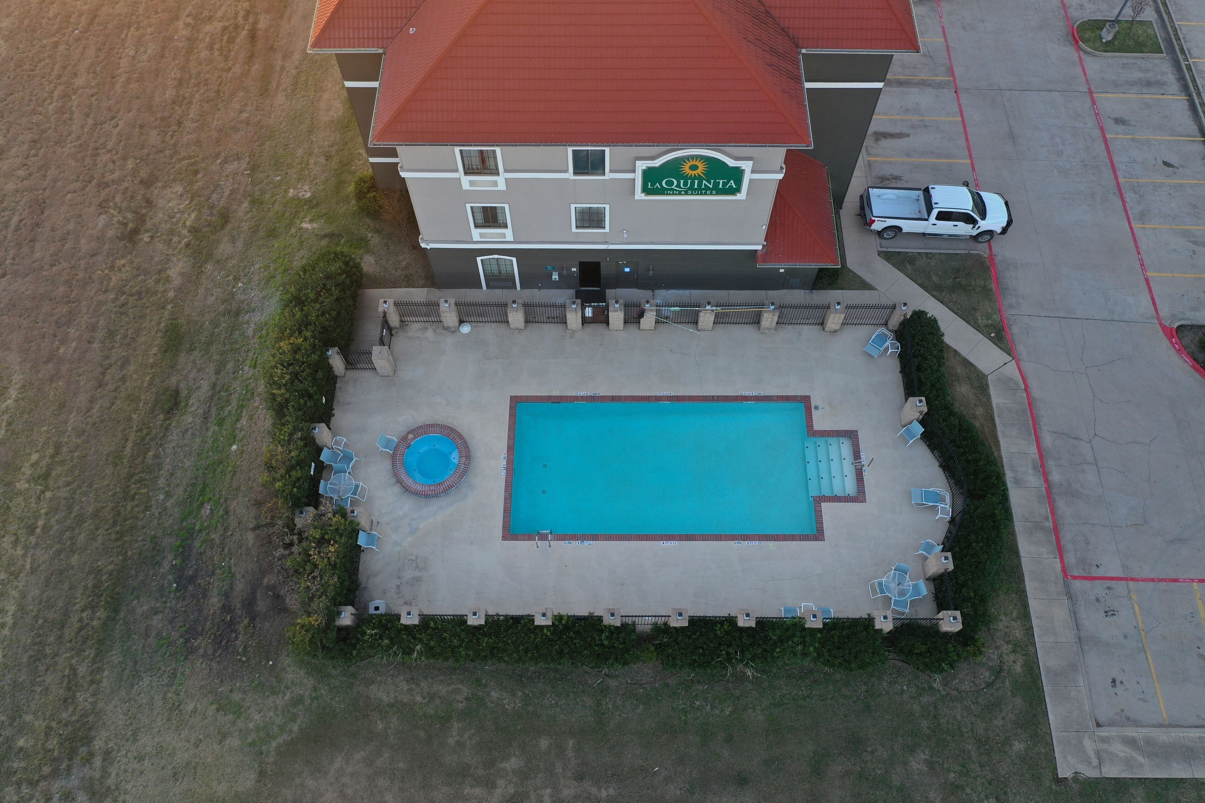 An aerial view of a hotel with a swimming pool, outdoor seating, and a parking lot.