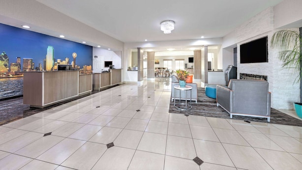 A hotel lobby with a reception desk, seating area, and a cityscape mural. - La Quinta Inn & Suites by Wyndham Alvarado (Alvarado)