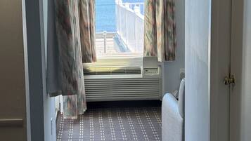 A narrow hallway with a patterned carpet, a window with curtains, and a view of the sea.