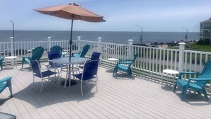 A deck with outdoor seating, a table, and an umbrella. - Atlantic House (Narragansett)