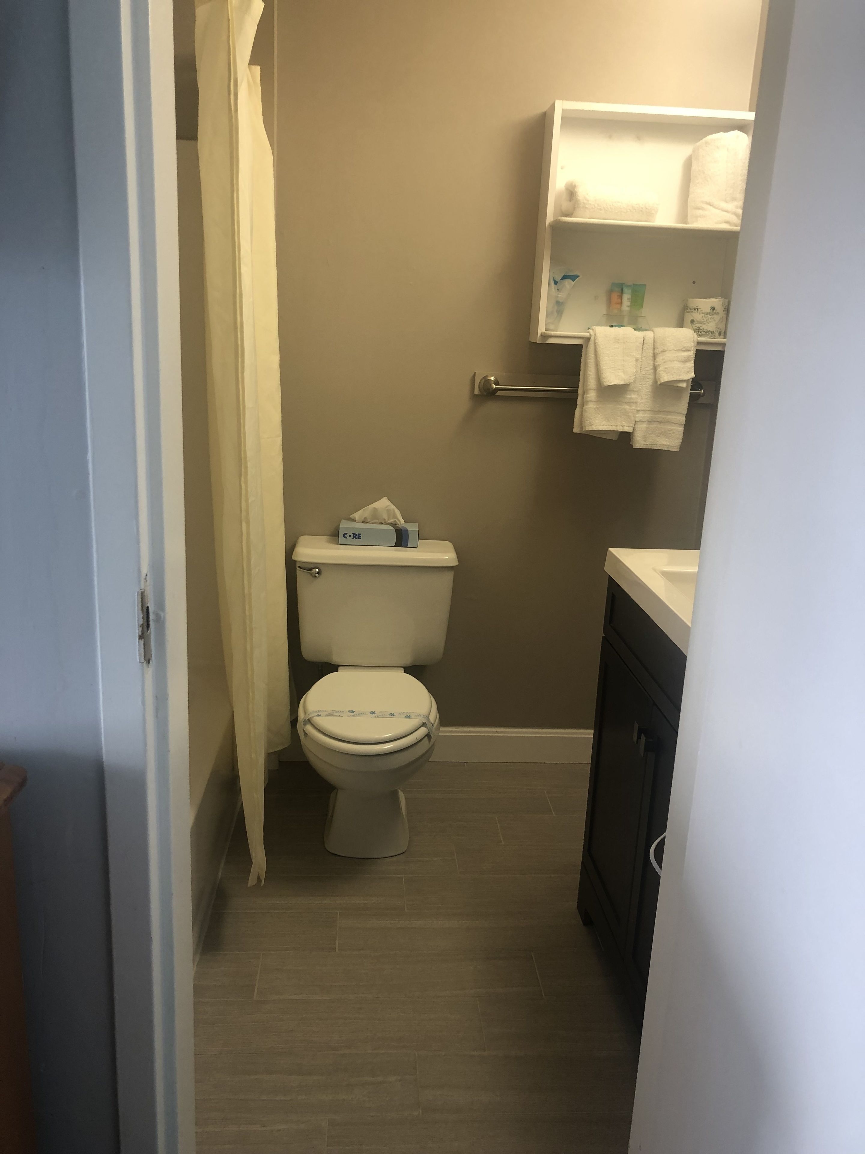 A small, compact bathroom with a toilet, a sink, and a towel rack.