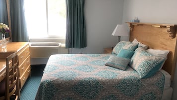 A bedroom with a bed, dresser, and window with curtains.