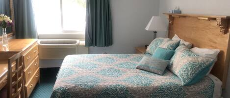 Un dormitorio con cama, cómoda y ventana con cortinas.