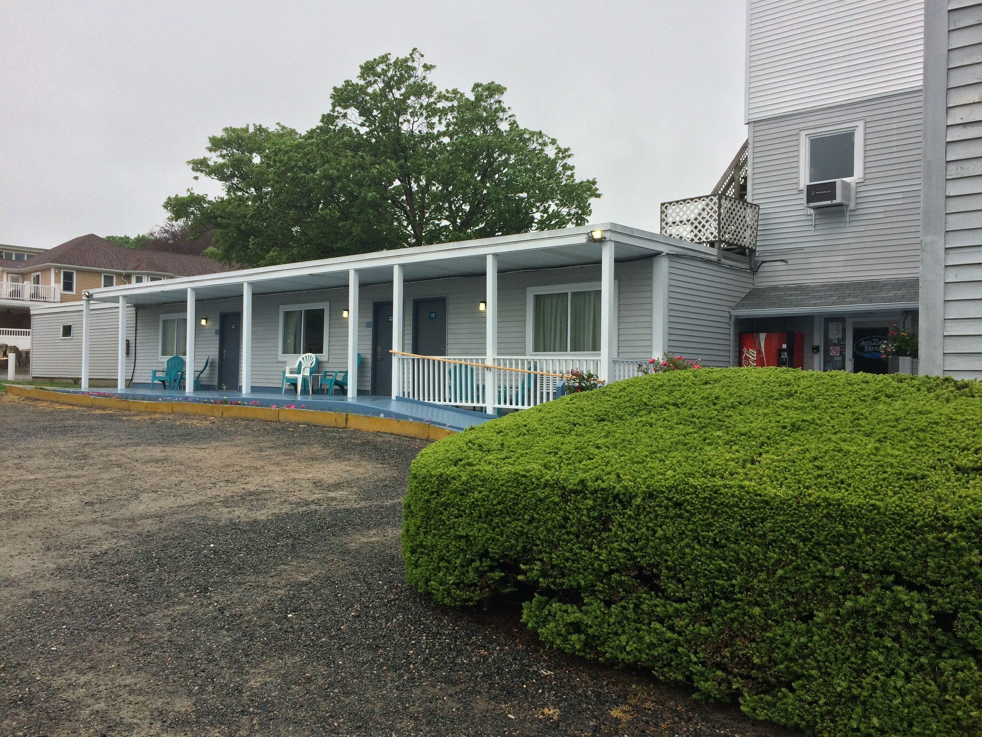 A motel with a covered porch, outdoor seating, and a Coca-Cola sign.