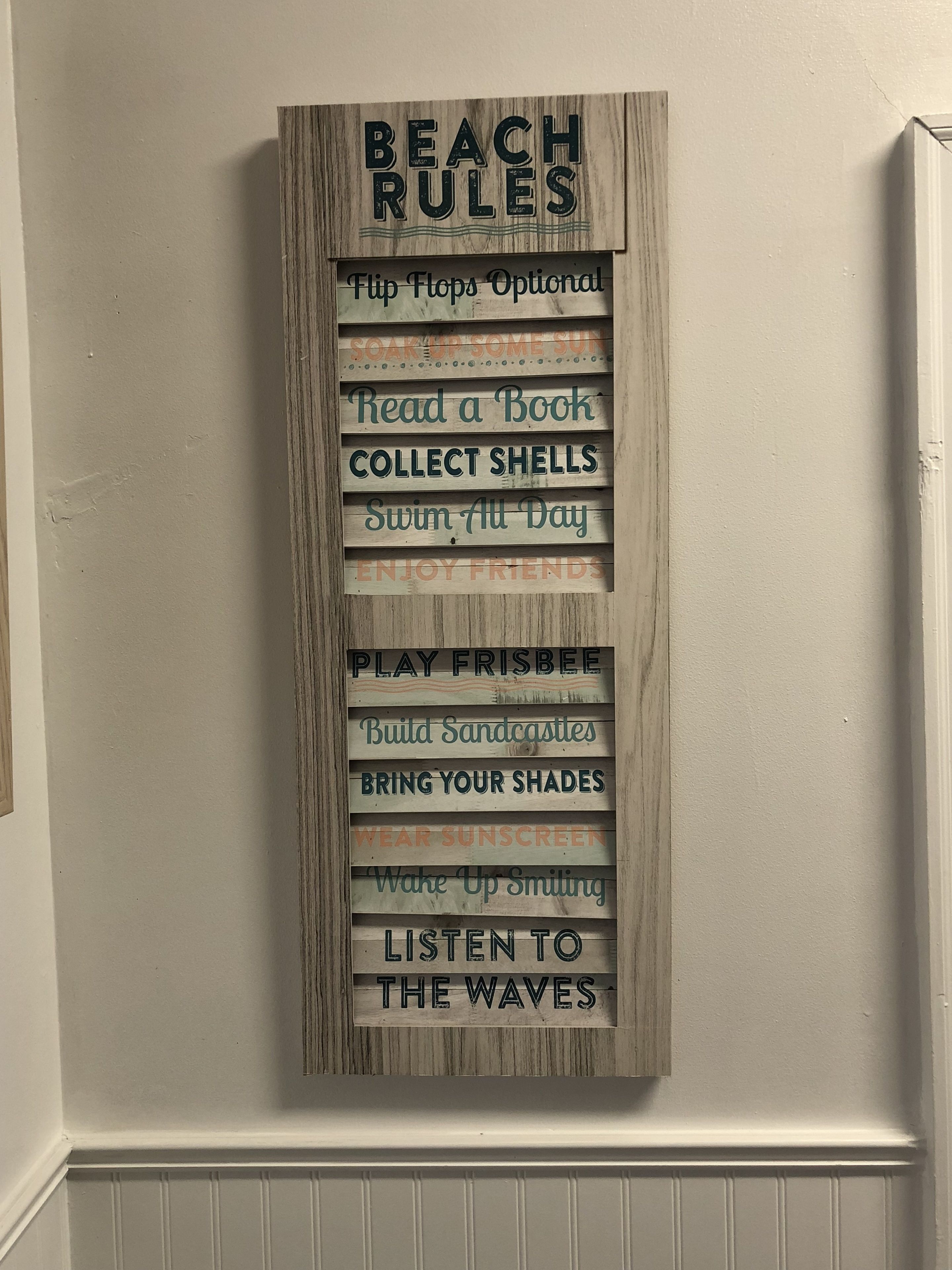 A wooden sign with 'BEACH RULES' and various activities listed, such as 'Read a Book' and 'Collect Shells'.