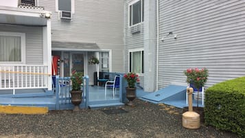 Un bâtiment doté d’un espace extérieur aménagé avec des sièges, d’un escalier et d’un petit jardin avec des plantes en pot.