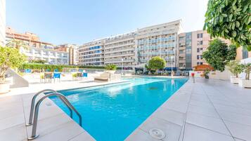 Een buitenzwembad en ligstoelen