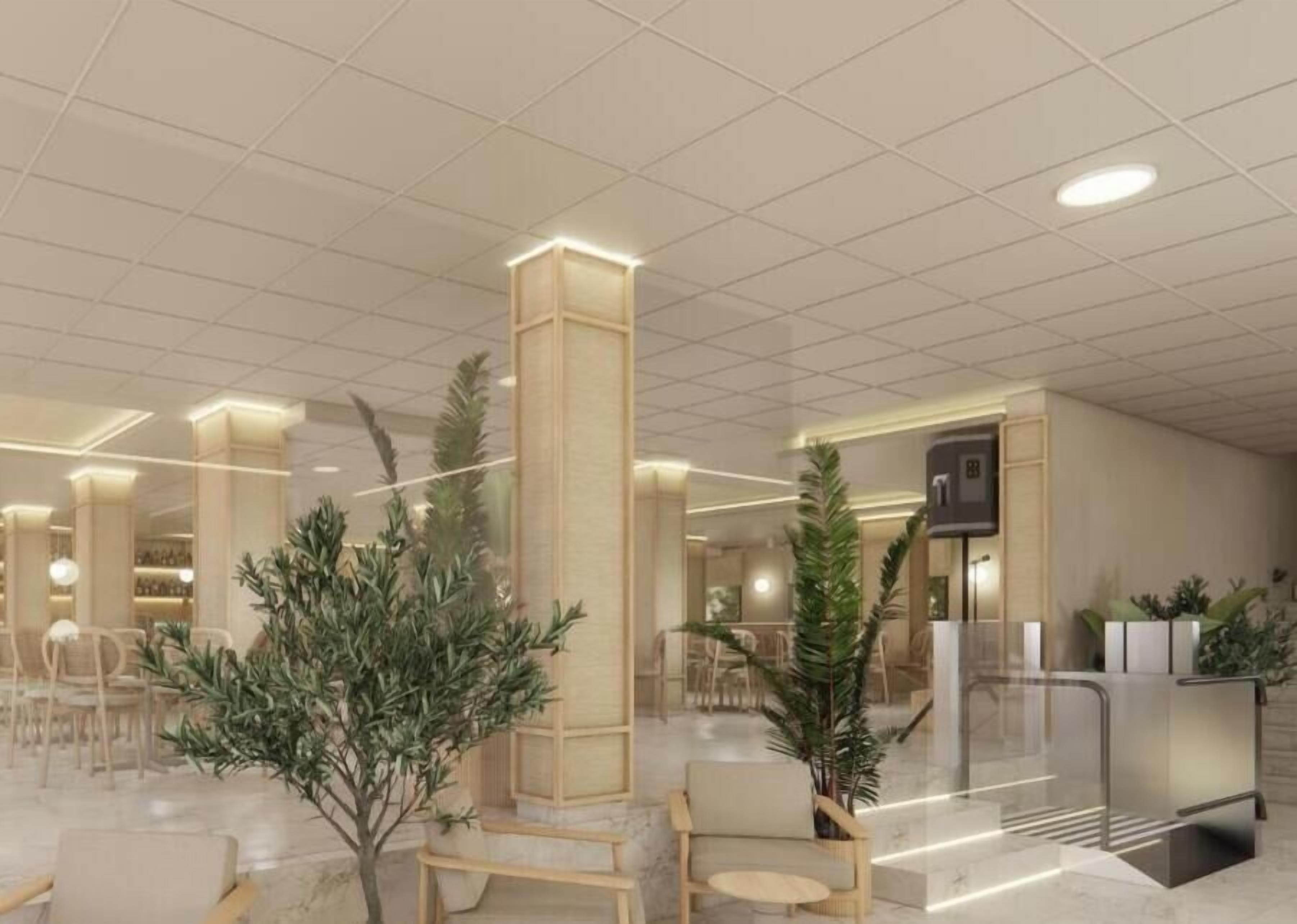 Un hall d’hôtel au design moderne, avec une colonne centrale, des espaces de détente et un comptoir d’accueil.