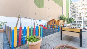 Un espace de jeux pour enfants avec un toboggan, une table de baby-foot et une petite maison en bois.