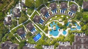 Luchtbeeld van een resort met meerdere bungalowgebouwen, een centraal gelegen zwembad en aangelegde tuinen.