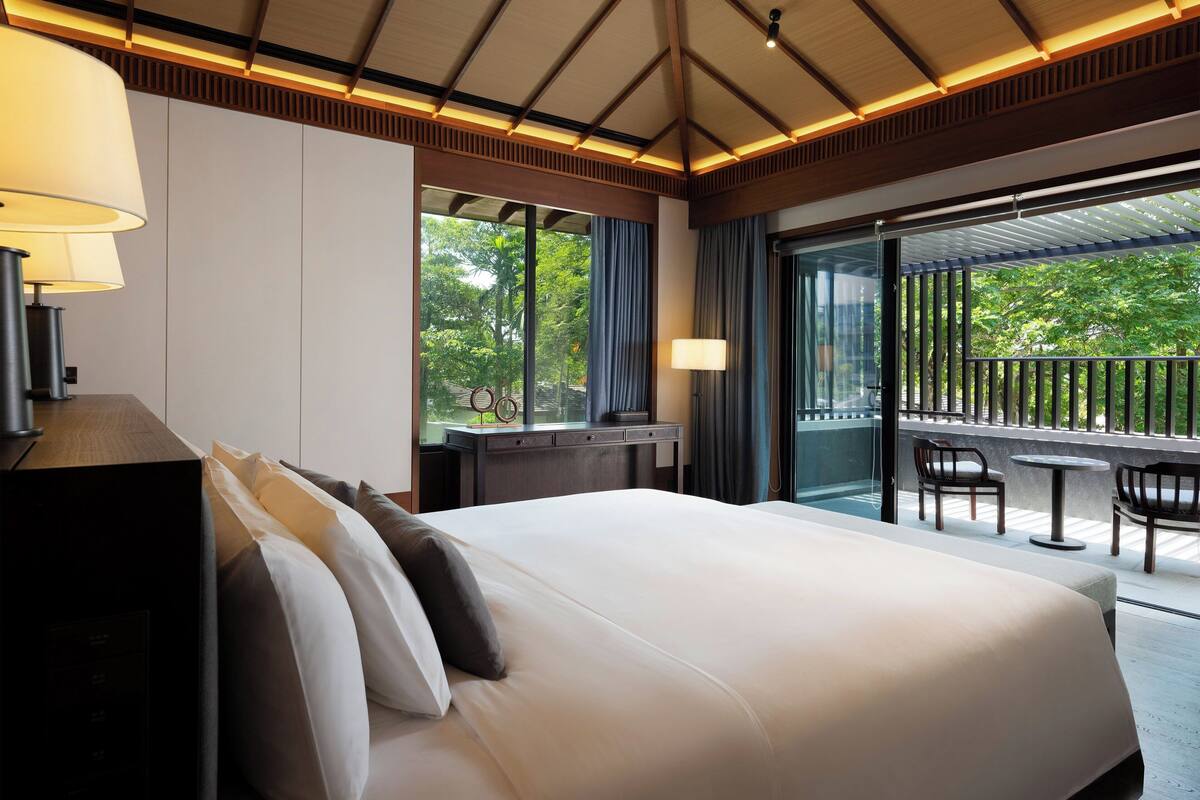 Une chambre d’hôtel dotée d’un grand lit, d’un bureau et d’un balcon avec des meubles d’extérieur.
