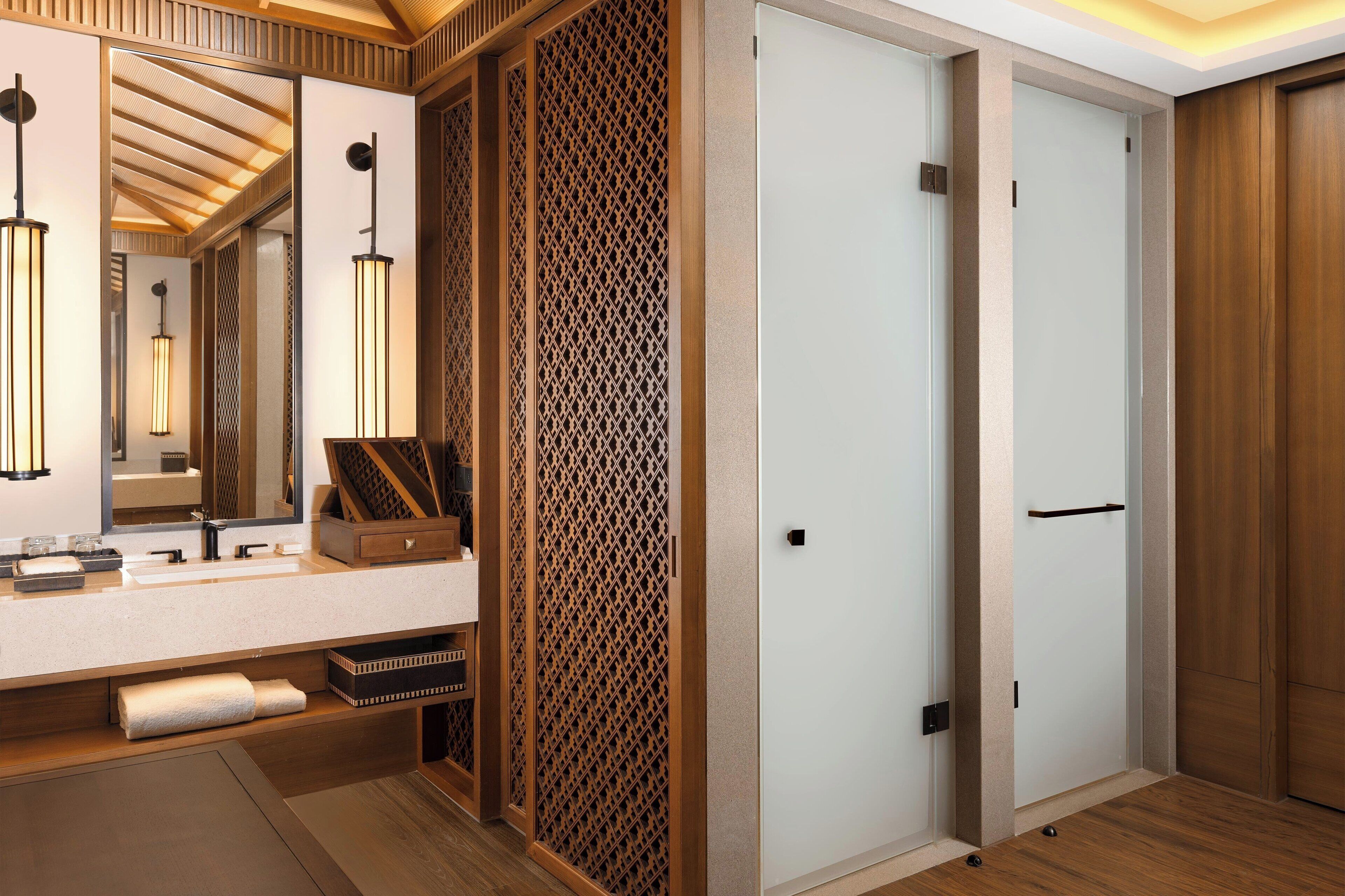 A modern bathroom with a large mirror, a wooden vanity, and a decorative partition.