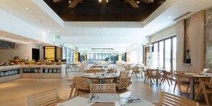 Un restaurante espacioso con mobiliario de madera y amplias ventanas.