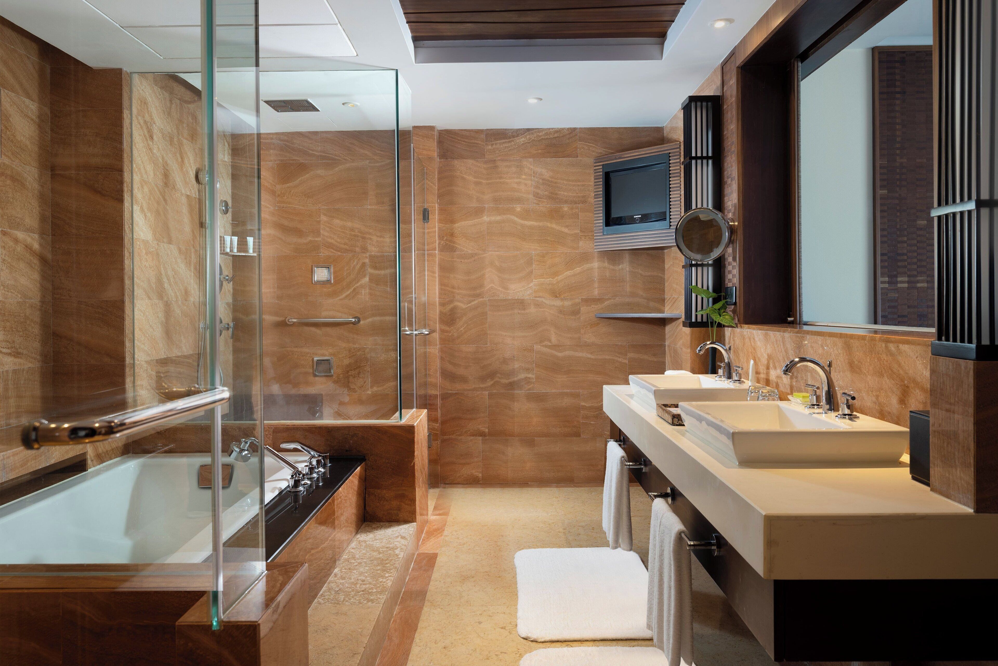 A modern bathroom with a glass-enclosed shower, a freestanding bathtub, and a vanity with two sinks.