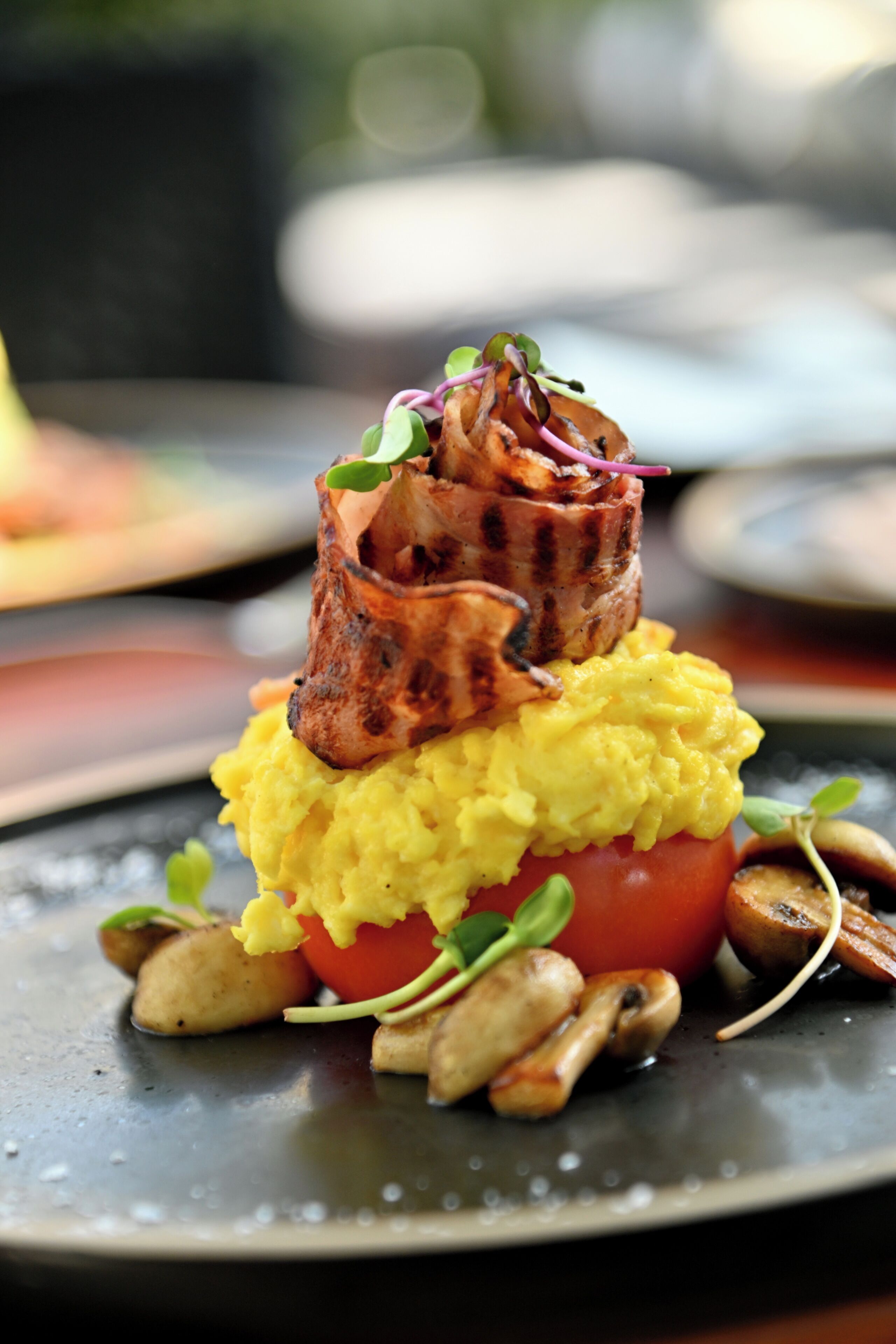 A plated dish with grilled meat, mashed potatoes, a tomato, and mushrooms.