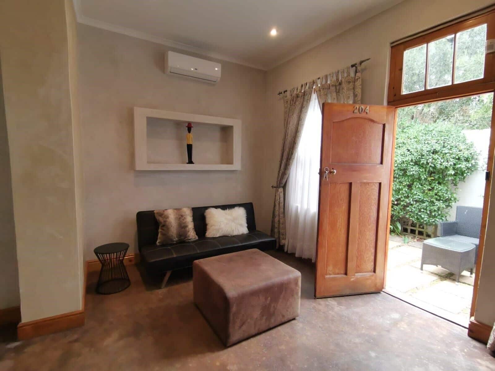 Una habitación con sofá, una mesita, una puerta de madera y una ventana.