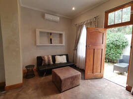 Una habitación con sofá, una mesita, una puerta de madera y una ventana.