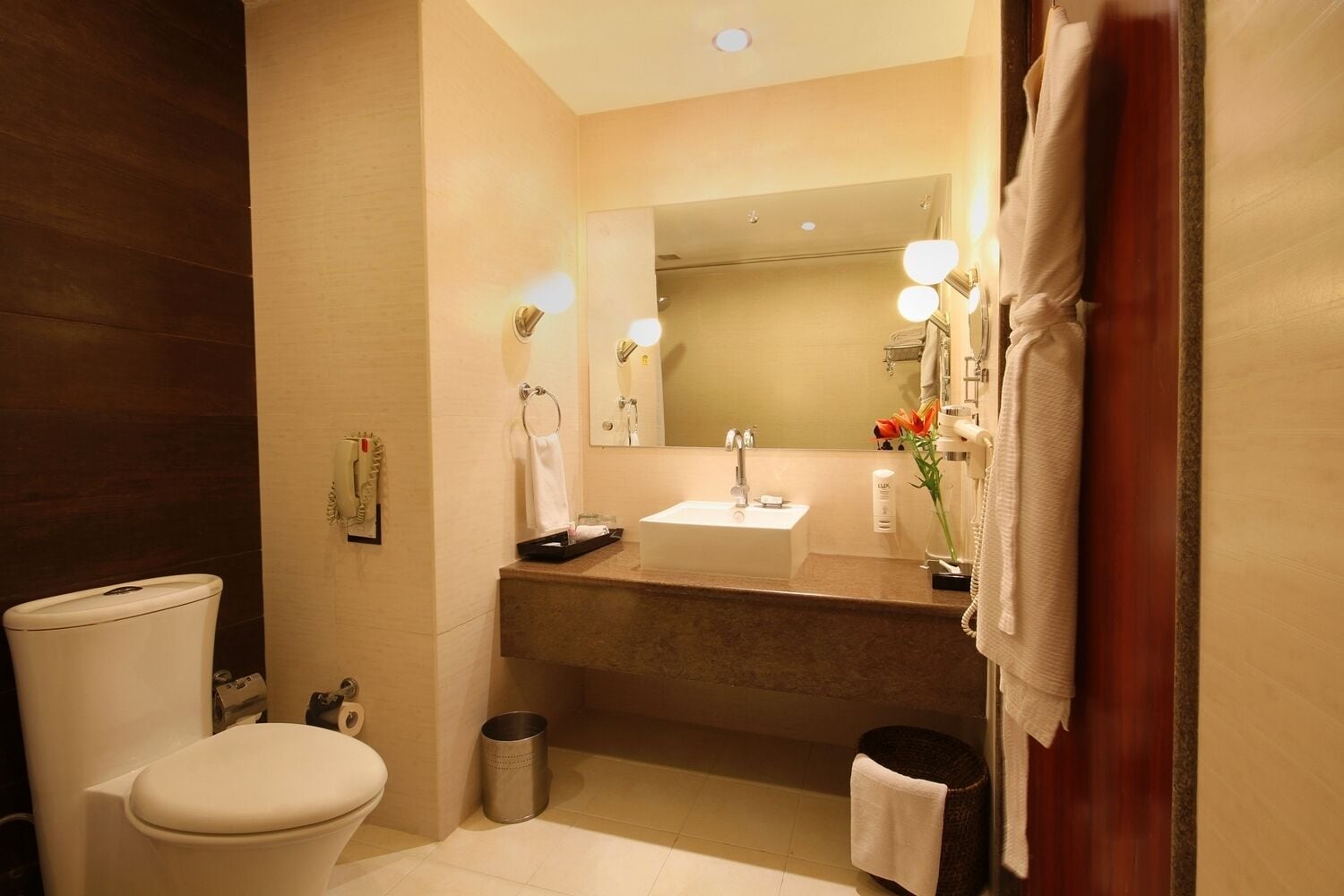 A modern bathroom with a toilet, sink, mirror, and vanity.