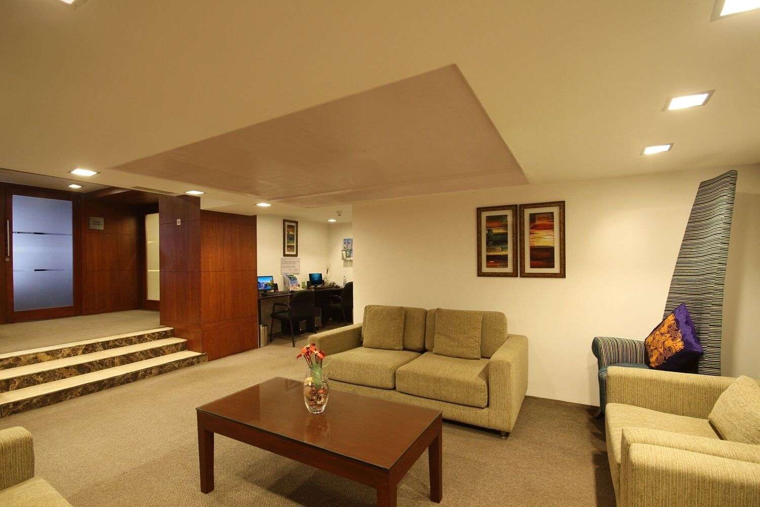 A lobby with a sofa, armchairs, a coffee table, and a reception desk.