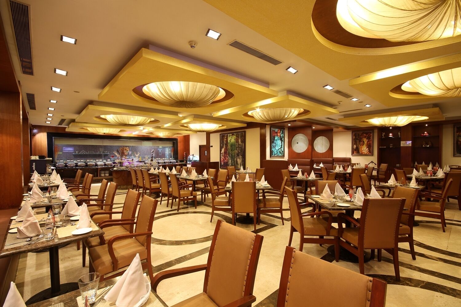 A spacious restaurant with multiple dining tables and chairs, a bar area, and modern ceiling lights.