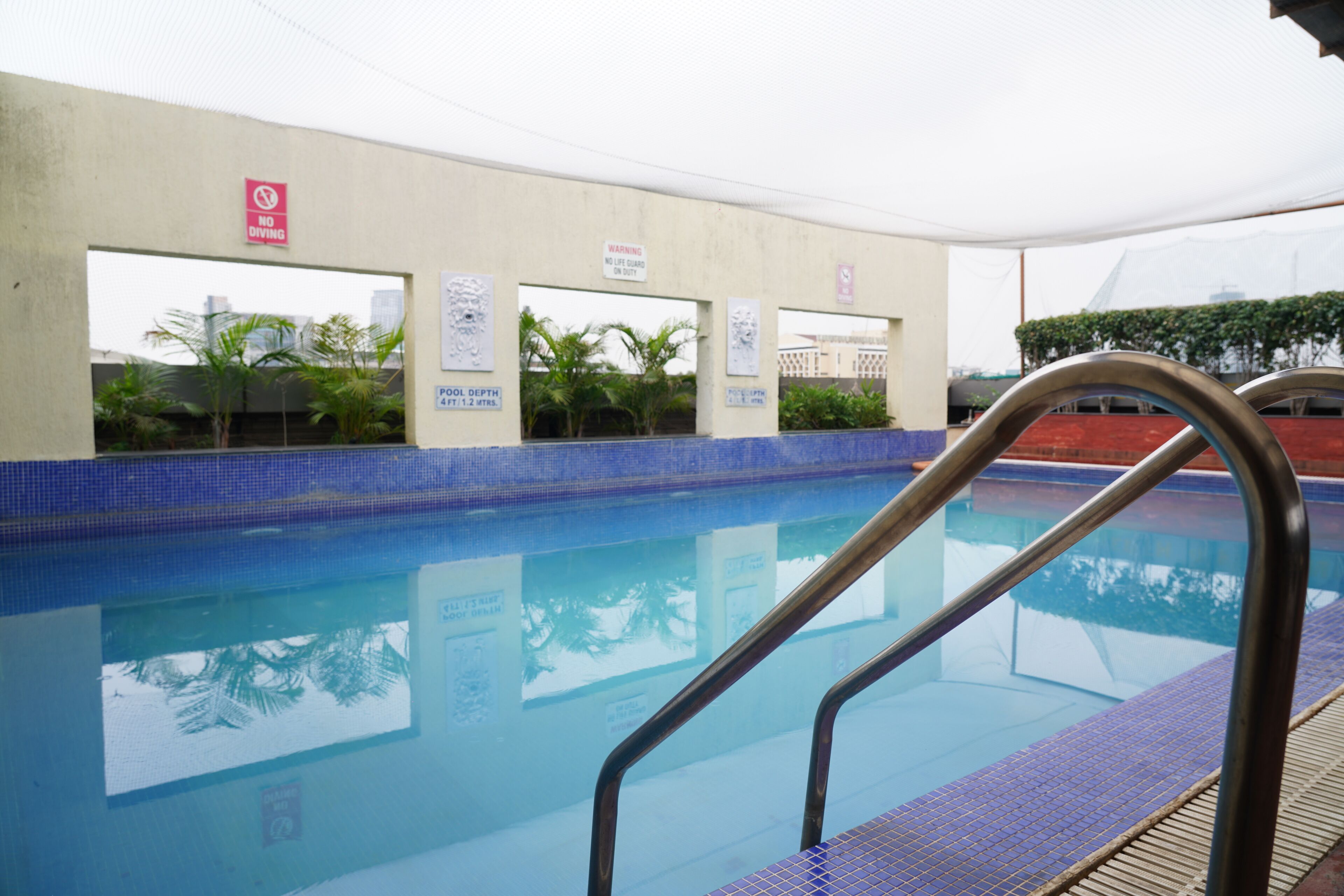 Una piscina con un cartel de prohibido bucear, un cartel de salvavidas y un indicador de profundidad.