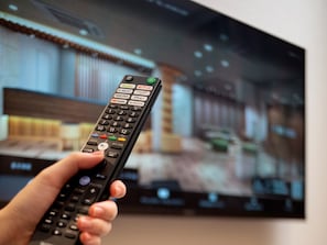 A hand holding a remote control with various channel and service buttons. - Hotel MyStays Asakusa (Tokyo)