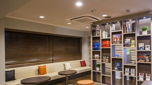 A modern hotel lobby with a seating area, a bookshelf, and a reception desk. - Hotel MyStays Asakusa (Tokyo)