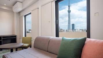 A modern living room with a sofa, a round table, and a view of a tower through large windows.