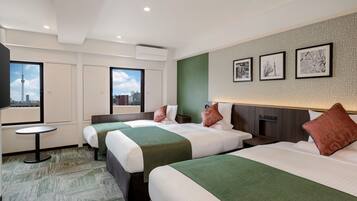 Quarto de hotel com duas camas, uma mesinha e vista para a cidade.
