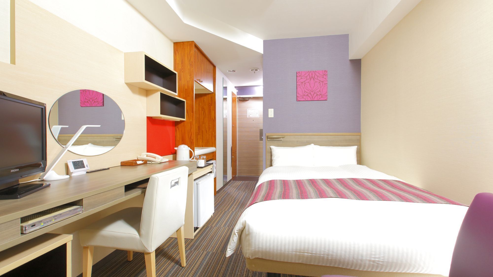 A hotel room with a bed, desk, chair, TV, and a mirror.