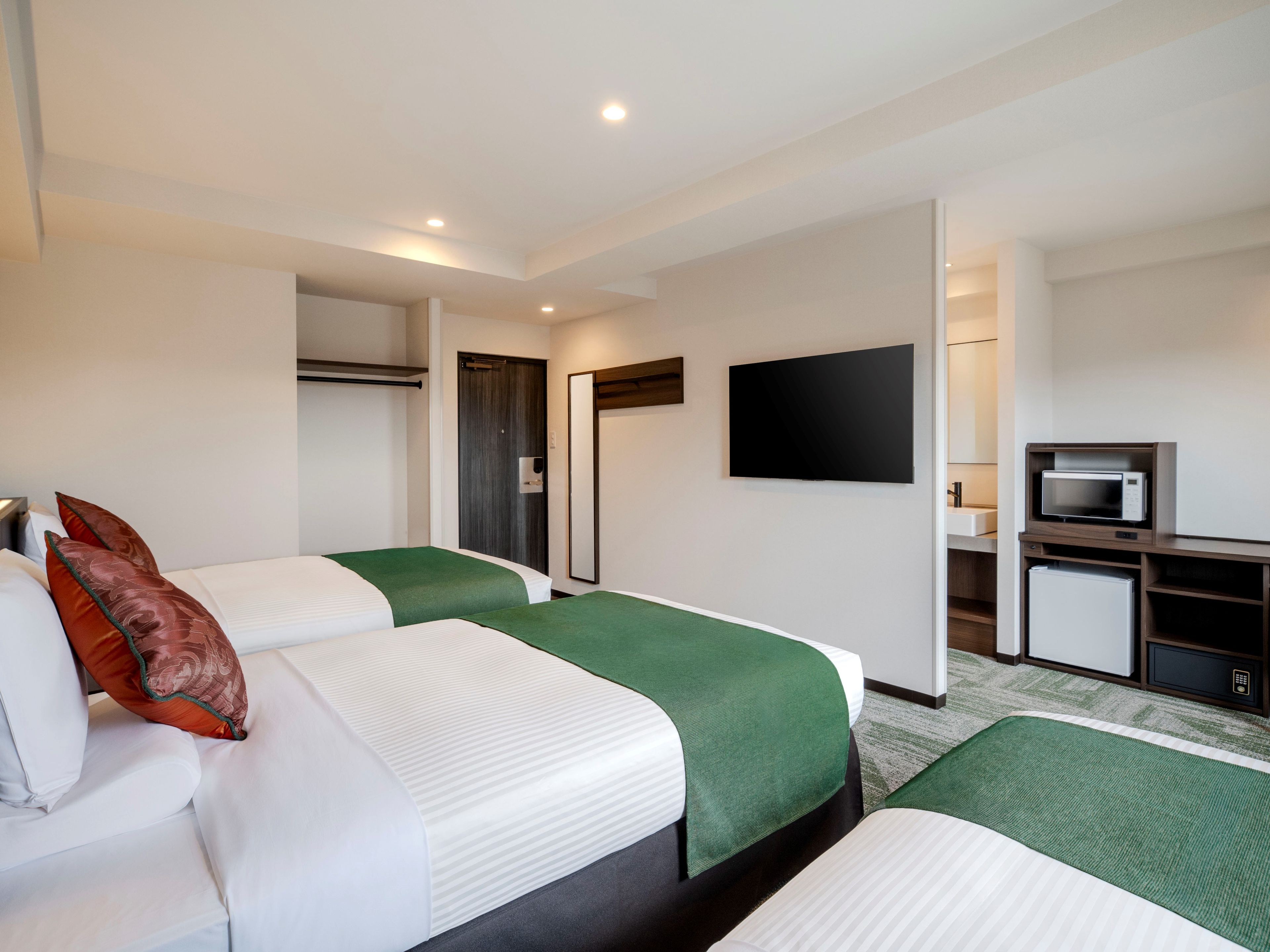 Ein Hotelzimmer mit zwei Betten, einem Fernseher, einer Mikrowelle und einem Kühlschrank.