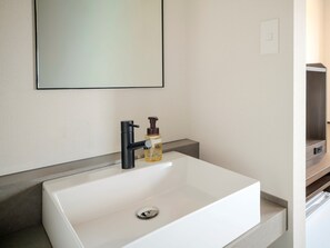 A white bathroom sink with a black faucet, a soap dispenser, and a mirror above it. - Hotel MyStays Asakusa (Tokyo)