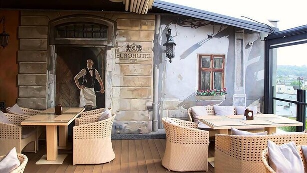 Un restaurante con mobiliario de mimbre, fachada de piedra y vistas a la ciudad.