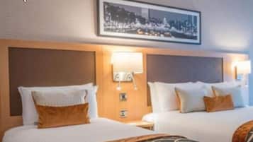 Habitación de hotel con dos camas, una fotografía de la ciudad en la pared y lámparas de noche.