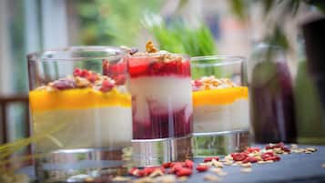 Three layered desserts in clear glasses with fruits and granola on a slate surface.