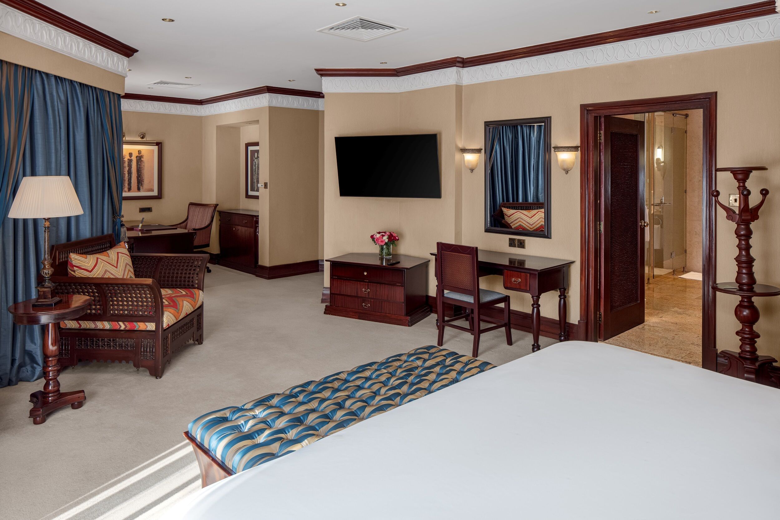 A hotel room with a bed, desk, chair, dresser, and a television.