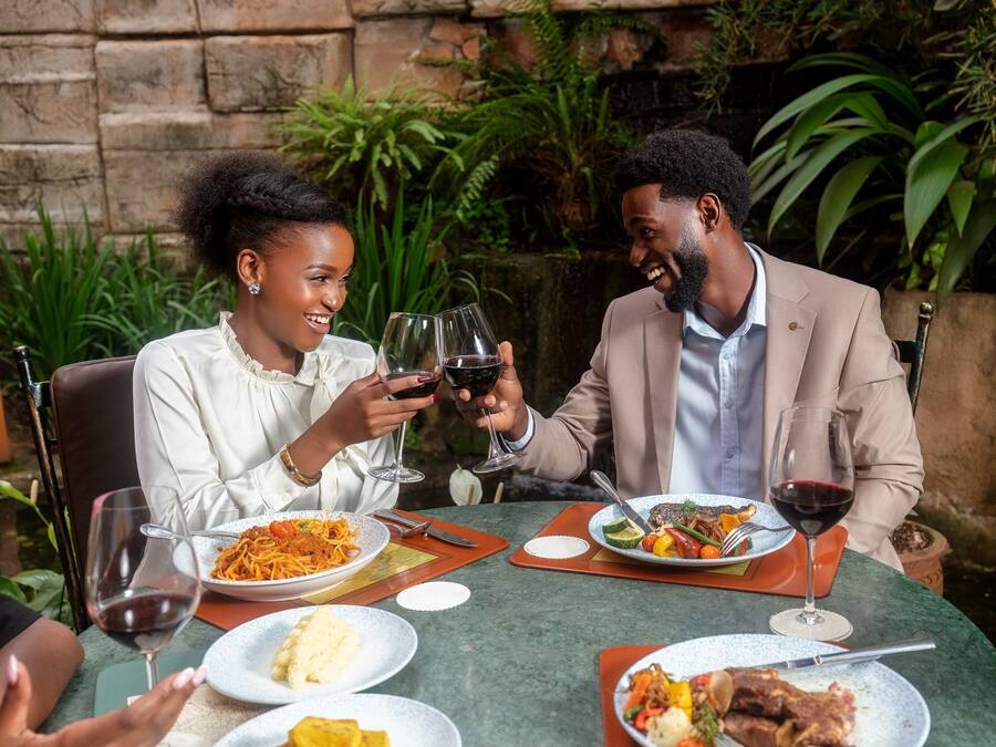Two people seated at an outdoor table with various dishes and wine glasses.