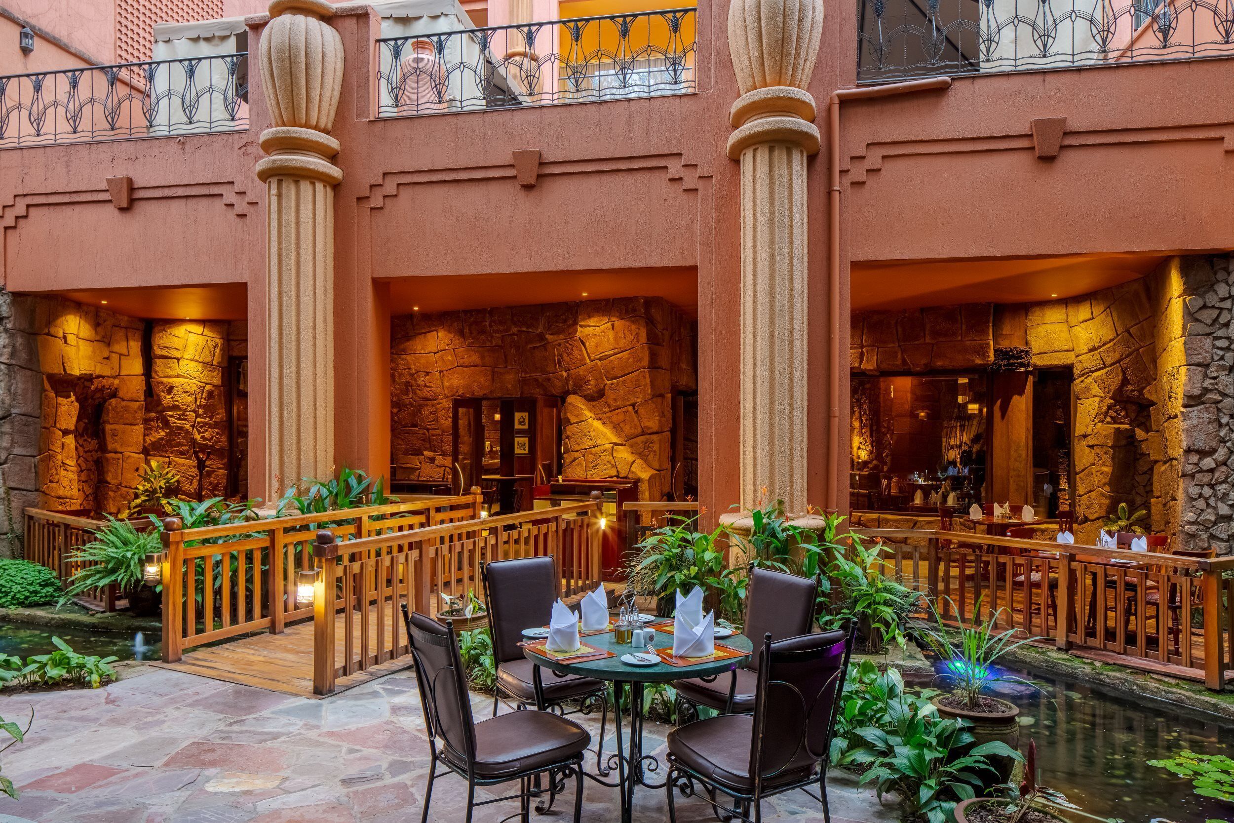 A restaurant with stone walls, wooden furniture, and a small water feature.