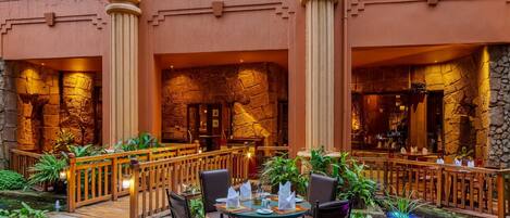 A restaurant with stone walls, wooden furniture, and a small water feature.