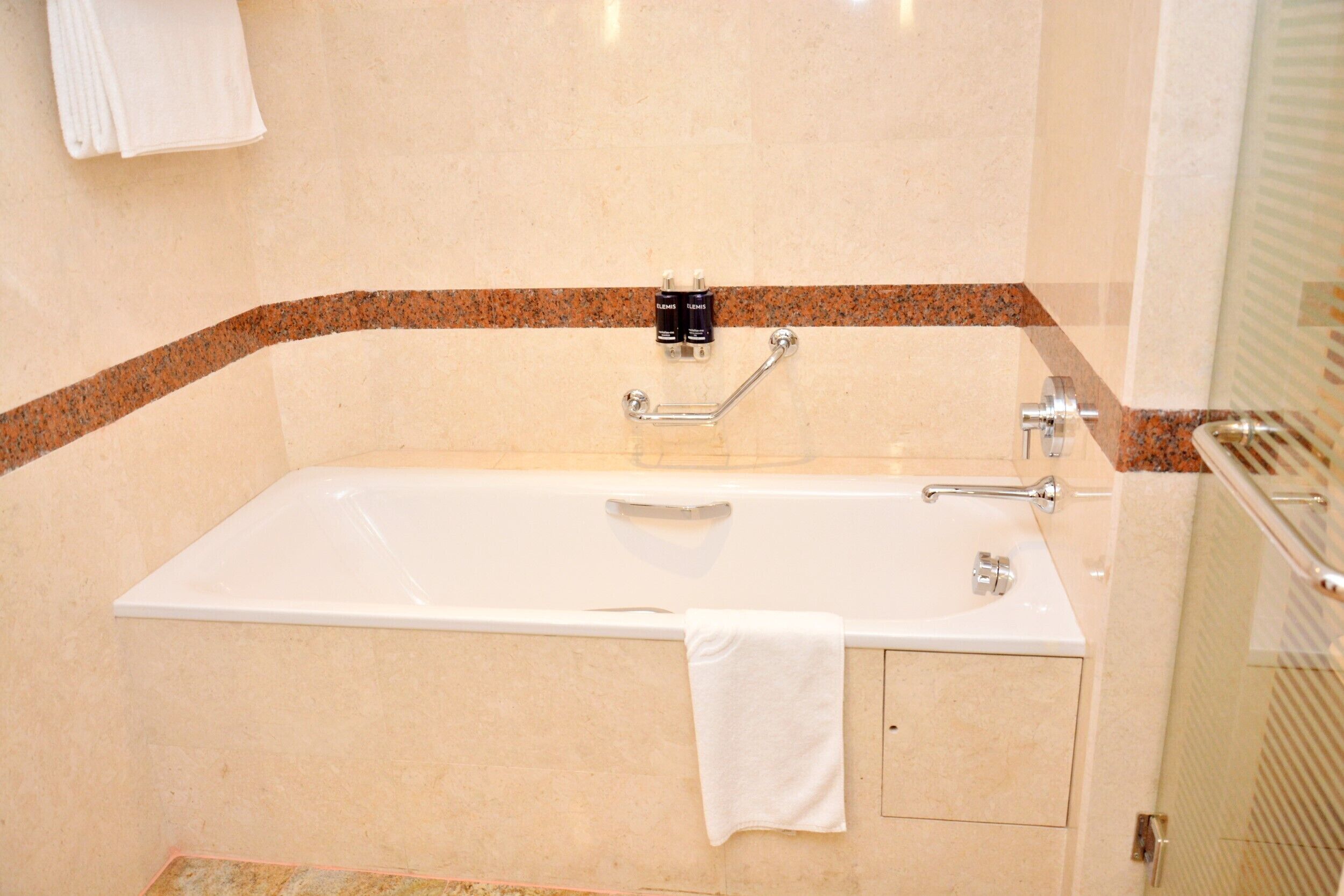 A bathroom with a white bathtub, a towel rack, and a shower area.