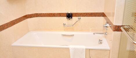 A bathroom with a white bathtub, a towel rack, and a shower area.