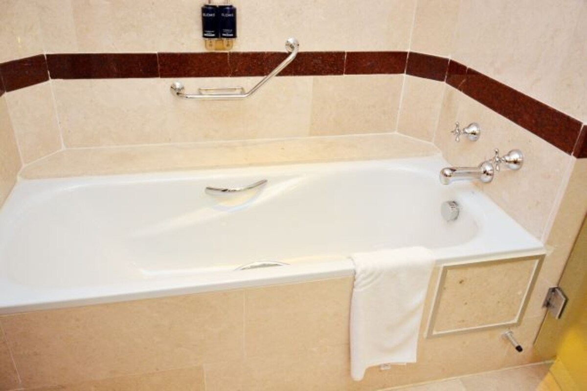 A standard hotel bathroom with a bathtub, a towel rack, and a shower control panel.
