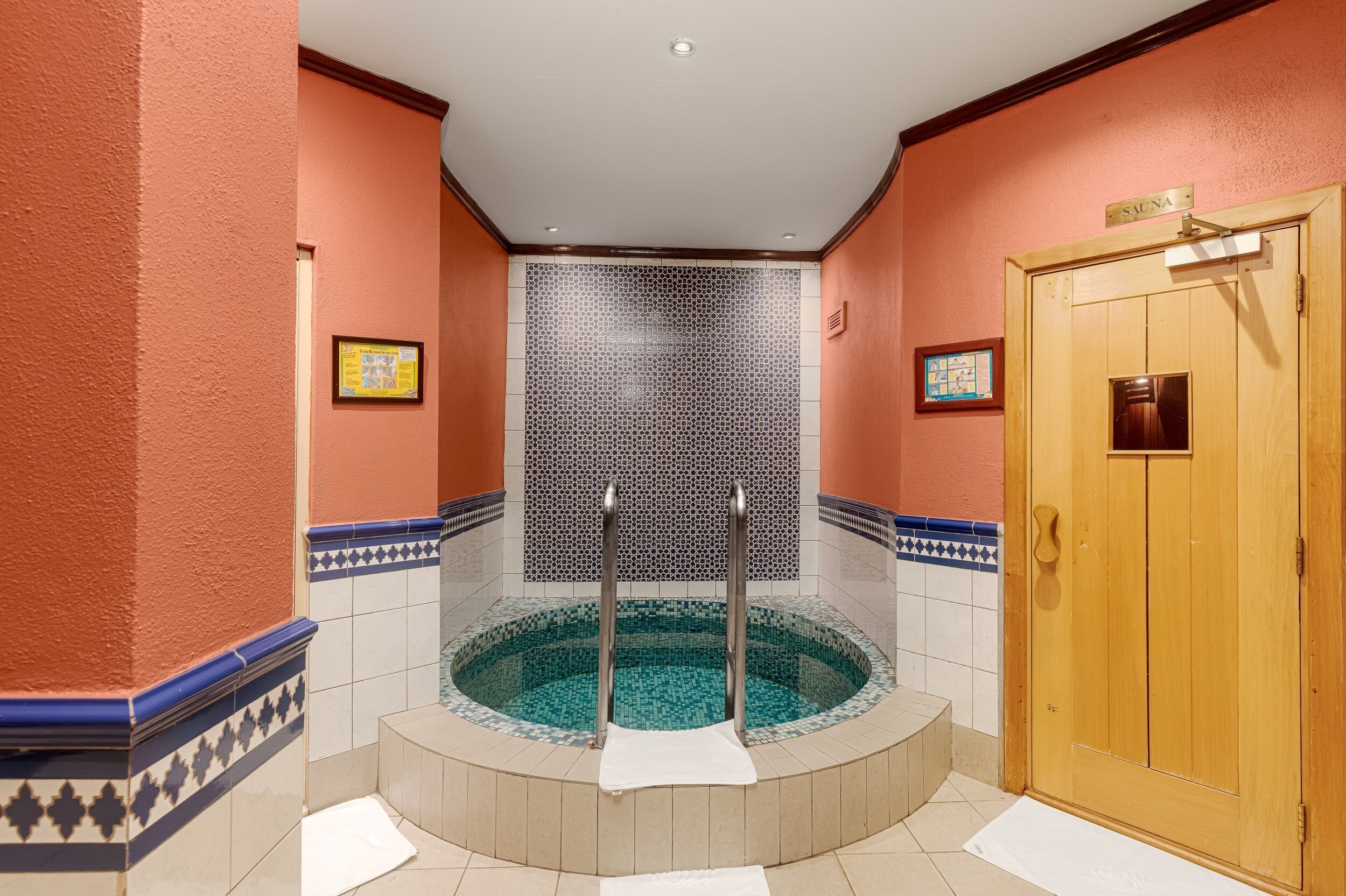 A spa area with a hot tub, a wooden door, and tiled walls.