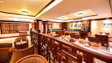 A hotel lobby with a traditional Asian design, featuring wooden furniture, a reception desk, and decorative screens.