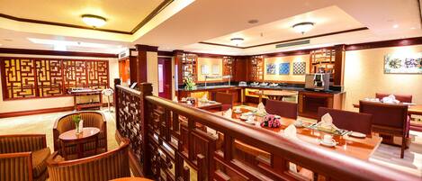 A hotel lobby with a traditional Asian design, featuring wooden furniture, a reception desk, and decorative screens.